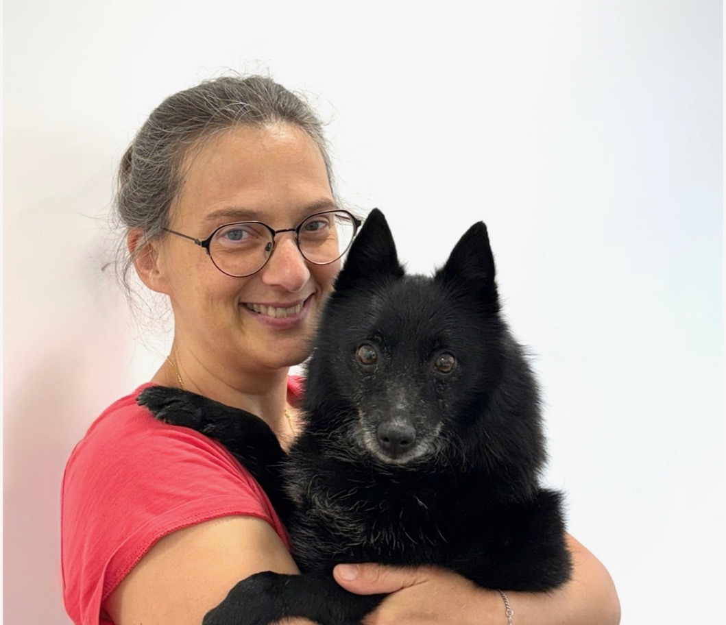 Portrait du Dr Isabelle Franzetti, vétérinaire pratique exclusive en acupuncture, avec un chien noir dans les bras